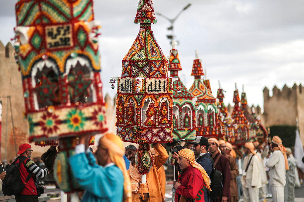 People carry large structures adorned with candles and religious phrases